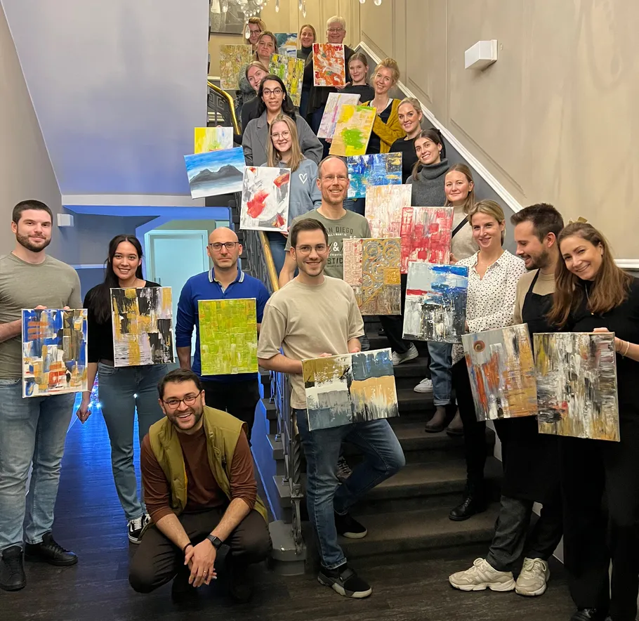 Group of people holding paintings on stairs.