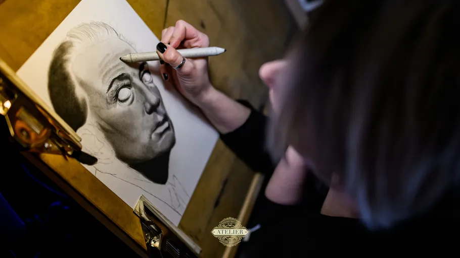 Artist shading portrait at drawing table.