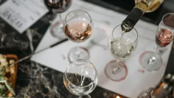 Wine glasses on table, one being filled.