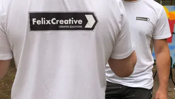 Two people wearing FelixCreative shirts outdoors.
