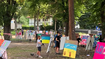 Children painting on canvases in a park.