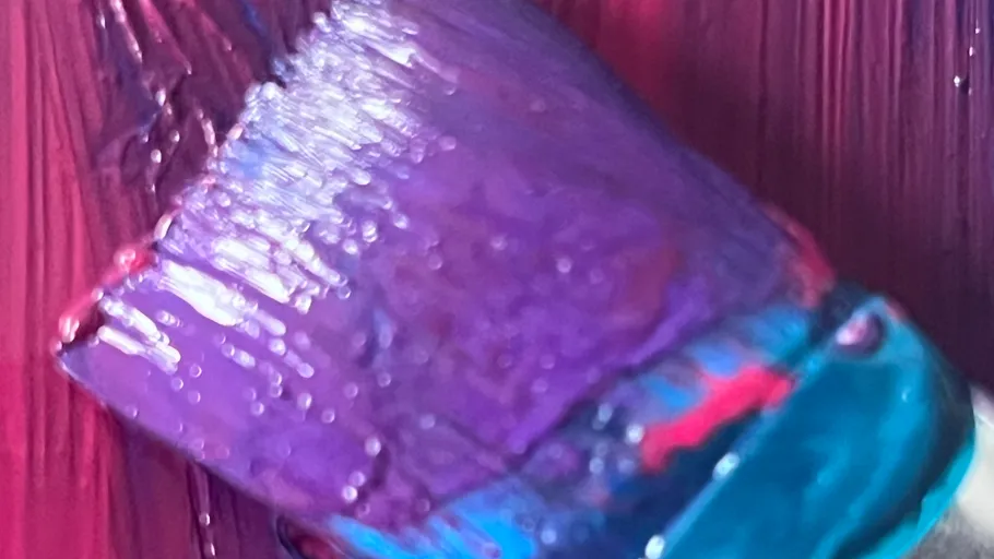 Paintbrush applying purple paint on canvas.