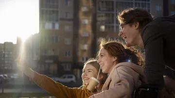 Drei Personen machen Selfie vor Gebäude.