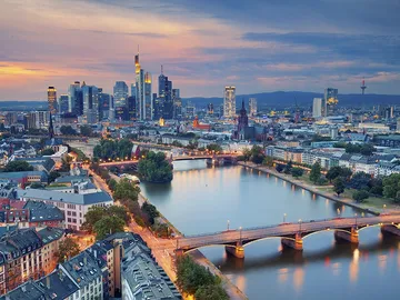 Stadtansicht mit Hochhäusern, Fluss und Abendhimmel.
