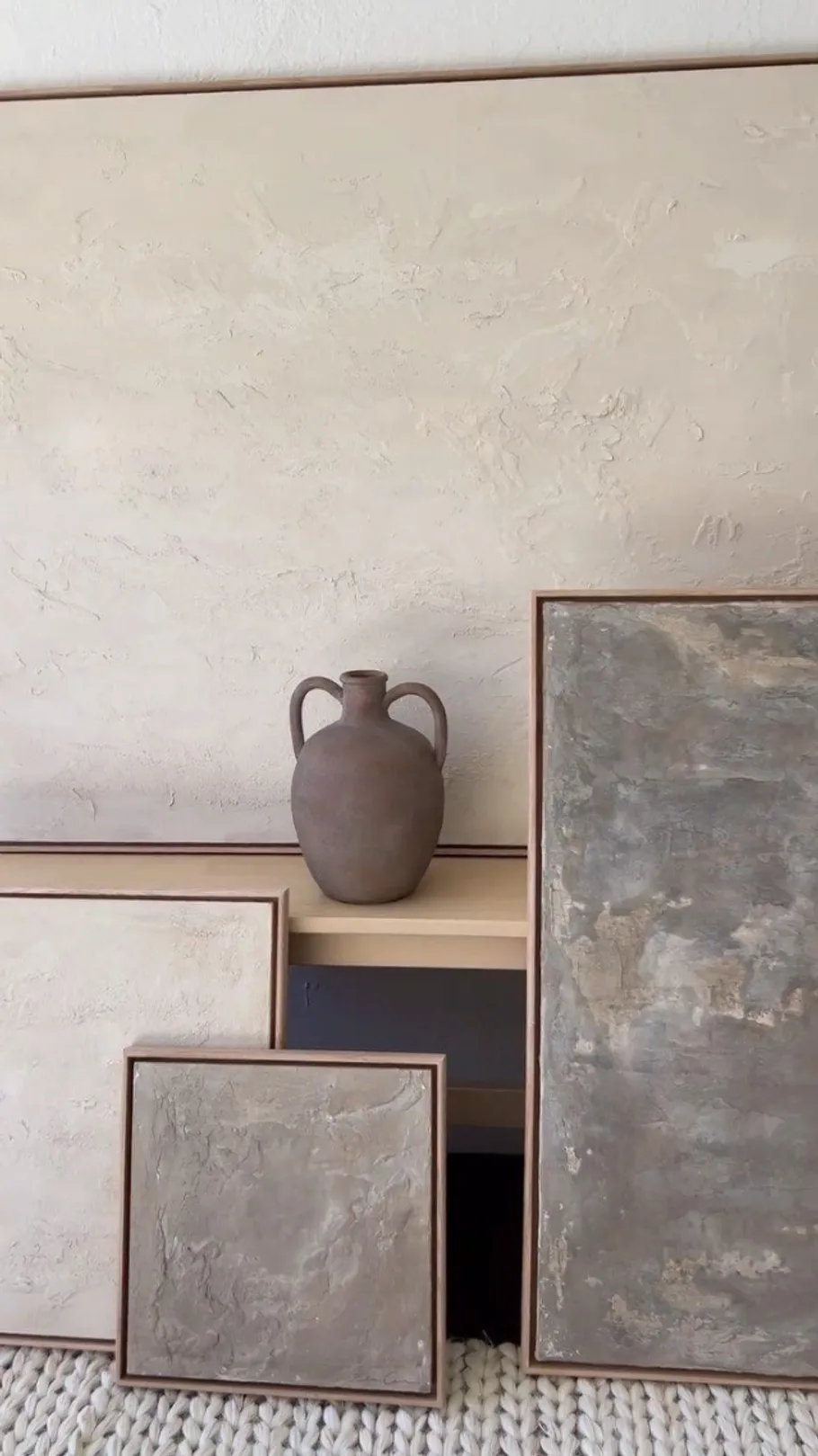 Vase auf Regal mit abstrakten Kunstwerken.