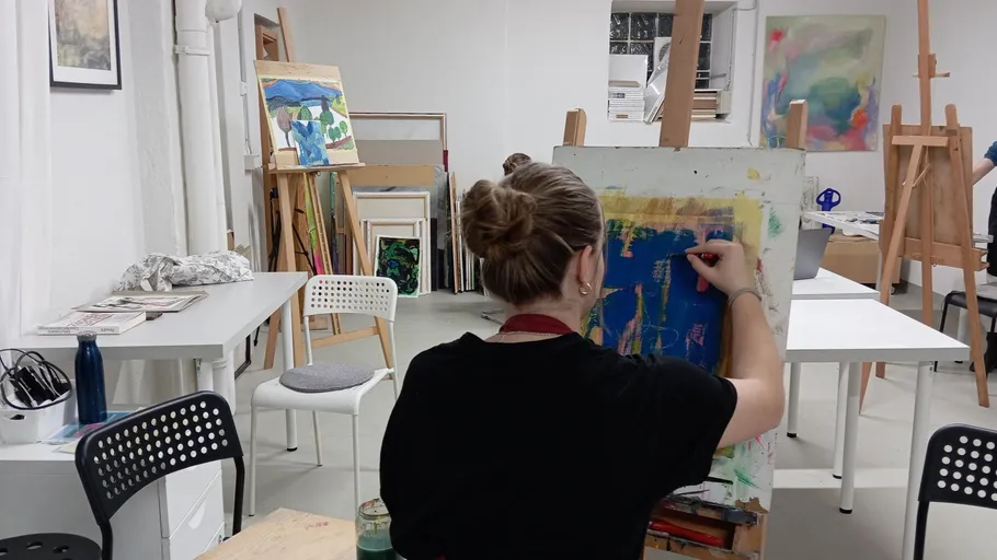 Person painting in art studio with easels.