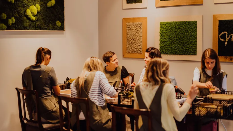 Gruppe beim Basteln drinnen, umgeben von grüner Wandkunst.