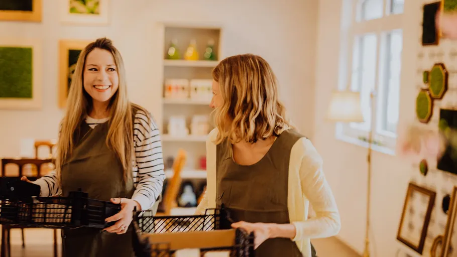 Two women smiling with baskets indoors.