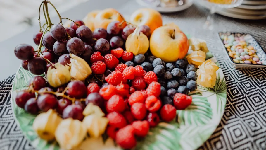 Obstteller mit Trauben, Himbeeren und Äpfeln.
