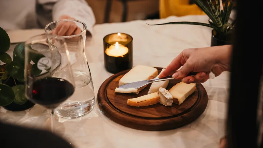 Cheese and knife on wooden platter, candle lit.