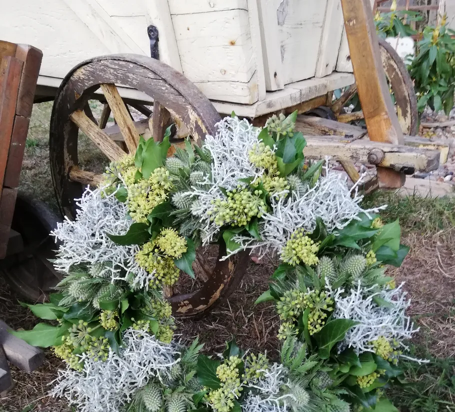 Blumenkranz auf altem Holzwagenrad.