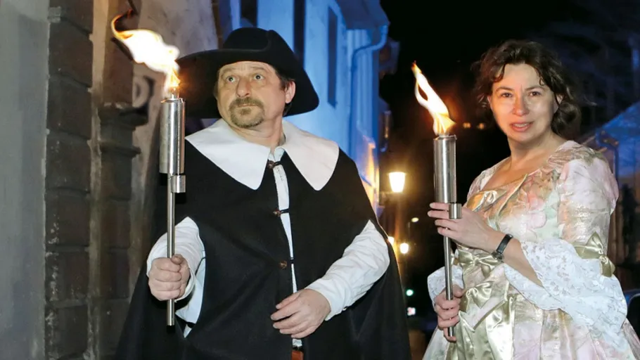 Two people holding torches at night outdoors.