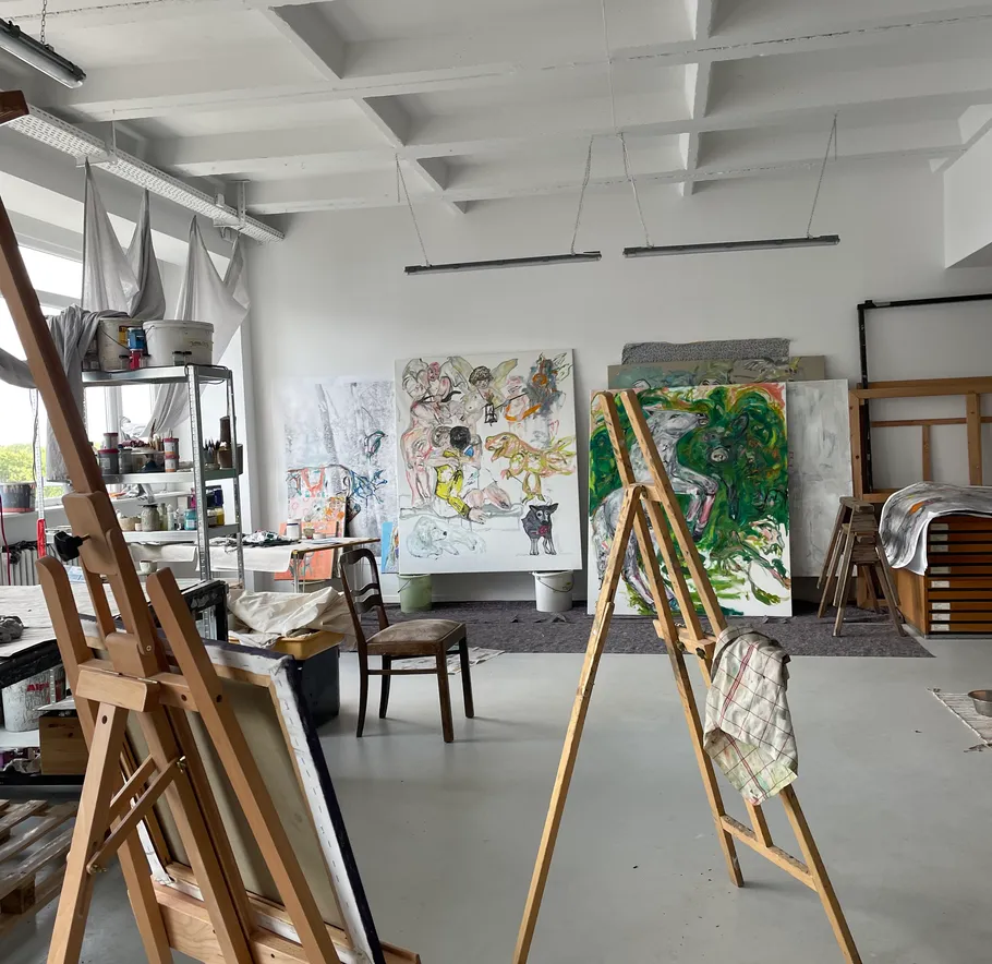 Kunststudio mit Staffeleien und bunten Gemälden.