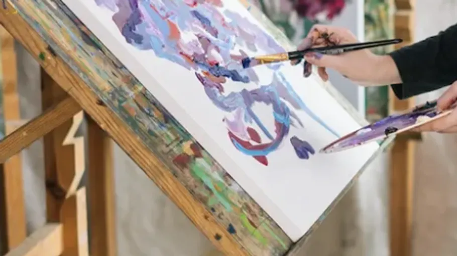 Person painting abstract art on easel.
