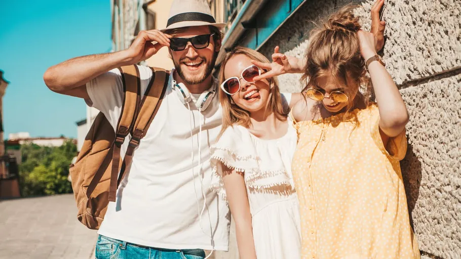 Three friends smiling outdoors in summer.