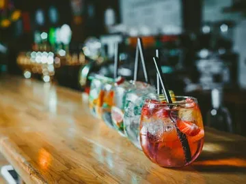 Bunte Cocktails stehen an einer Holzbar.