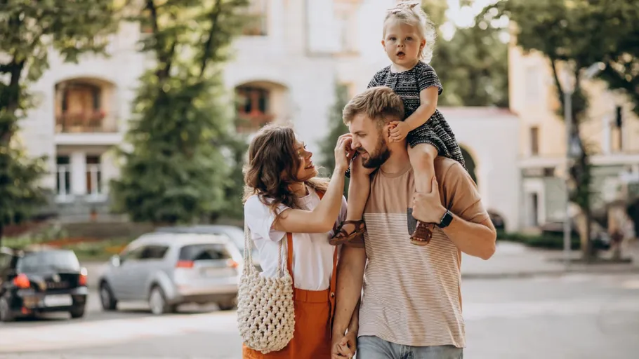Family walking outdoors, child on father's shoulders.