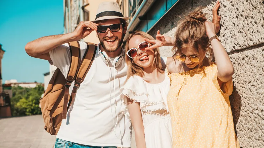 Three friends smiling outdoors in sunlight.