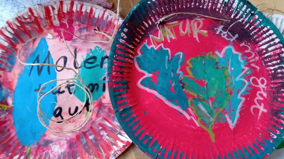 Bemalte Pappteller mit bunten Designs, Text.