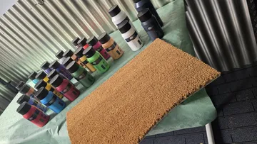 Farbflaschen auf Tisch neben Teppich ausgestellt.