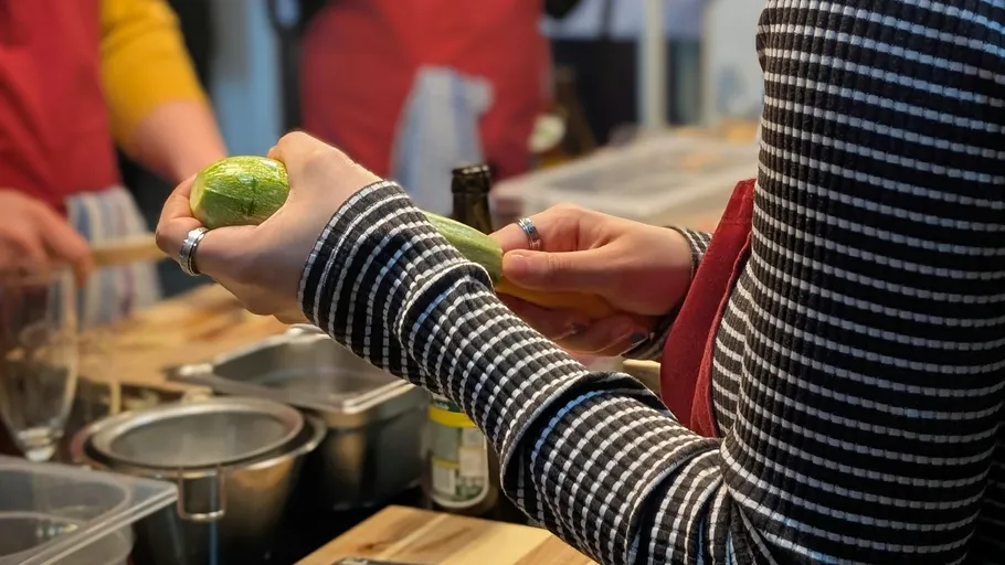 Person peeling zucchini in kitchen setting.