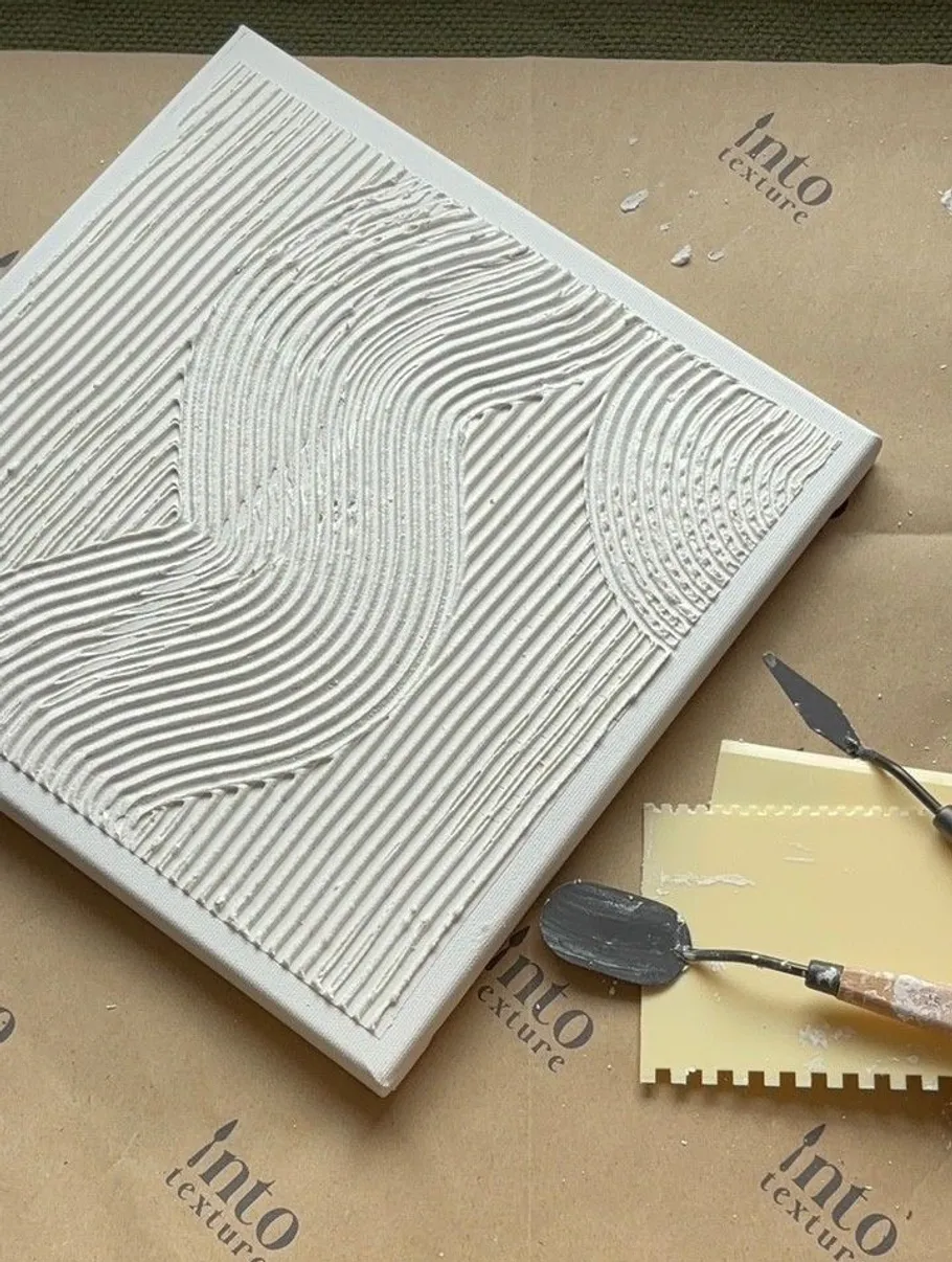 Textured artwork on canvas with painting tools nearby.