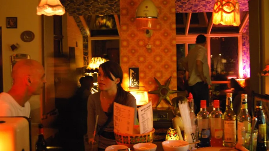 Menschen sprechen an einer schwach beleuchteten Bar mit Flaschen.