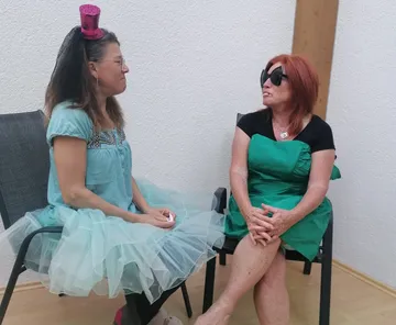 Two women sitting and talking indoors.