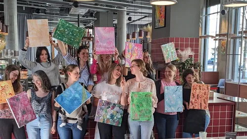Group holding paintings in a modern cafe.