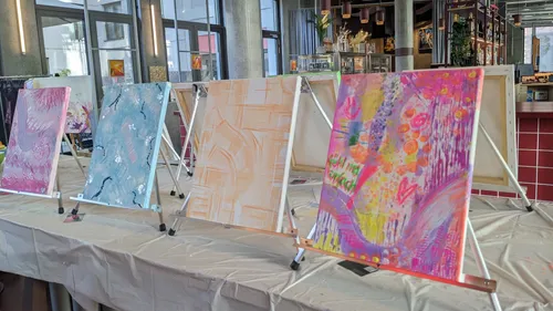 Colorful abstract paintings on easels indoors.