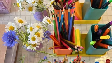 Buntstifte und Blumen auf Fliesenoberfläche.