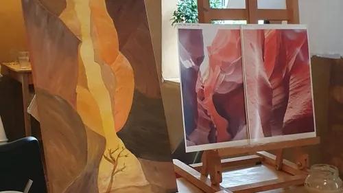 Painting easel with two canyon images indoors.