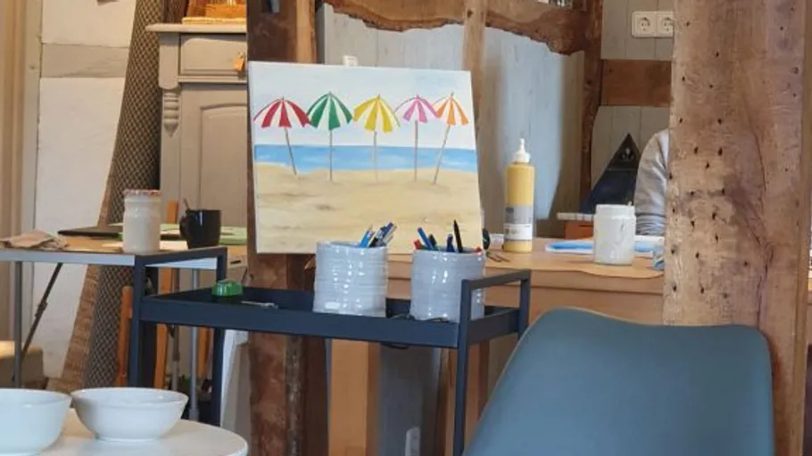 Unfinished beach painting in art studio setting.