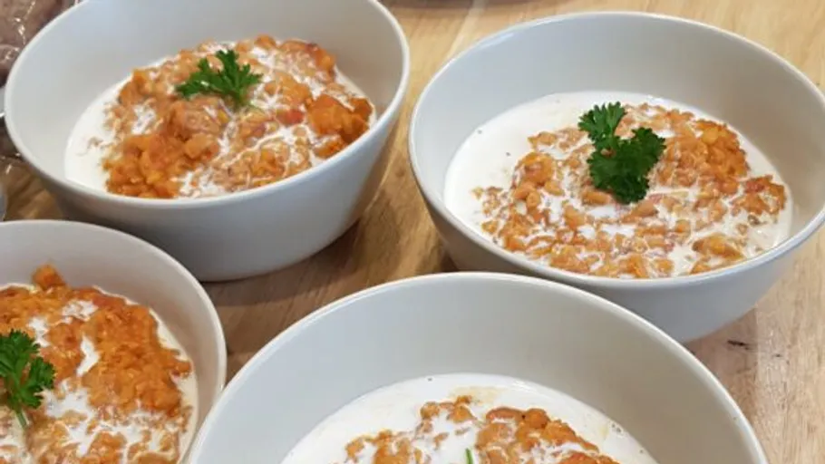 Four bowls with creamy lentil soup topped with parsley.