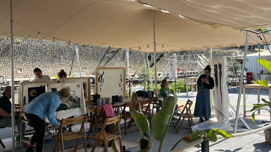 People creating art outdoors under canopy.