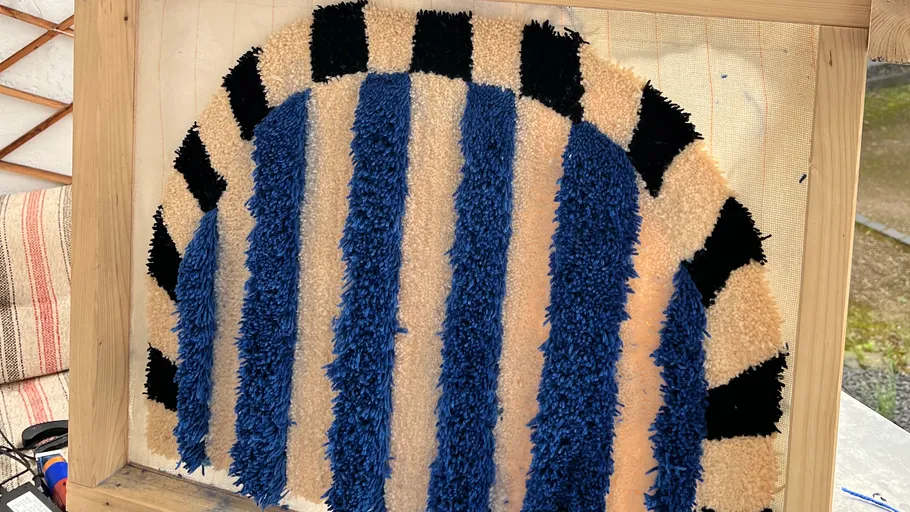 Bunt getuftetes Textil mit Streifen auf Leinwand.