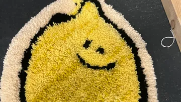 Lächelnder zitronenförmiger Teppich auf dunklem Boden.