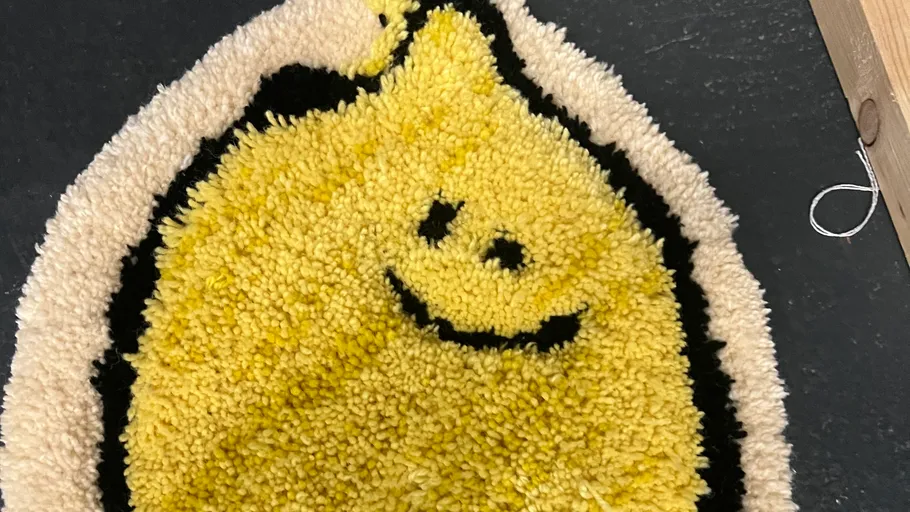 Smiley lemon-shaped rug on dark floor.