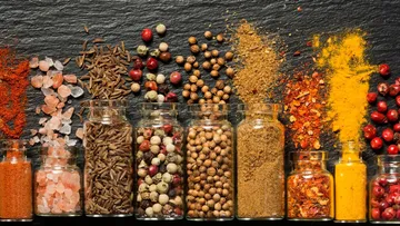 Jars of spices arranged on dark surface.