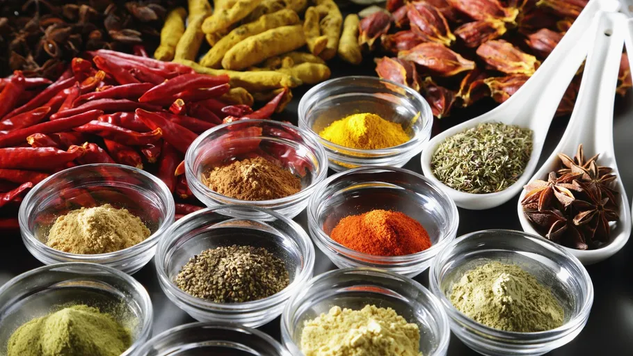 Assorted spices in bowls on black background.