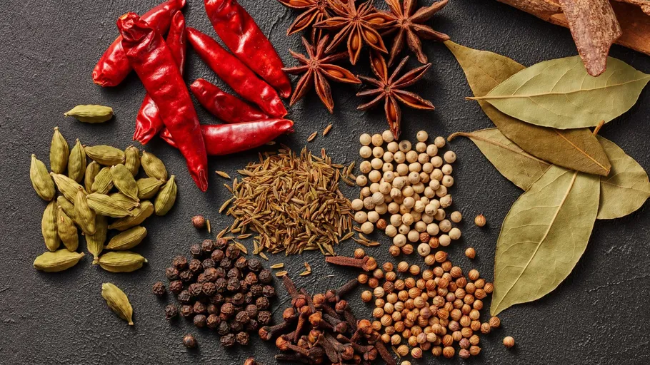 Various spices arranged on dark surface.