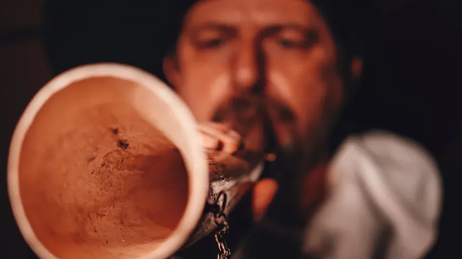 Musician blowing into a wooden instrument.