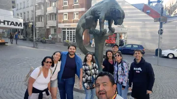 Group posing near large feline sculpture outdoors.