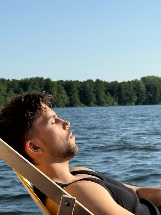 Man relaxing on deck chair by lake.
