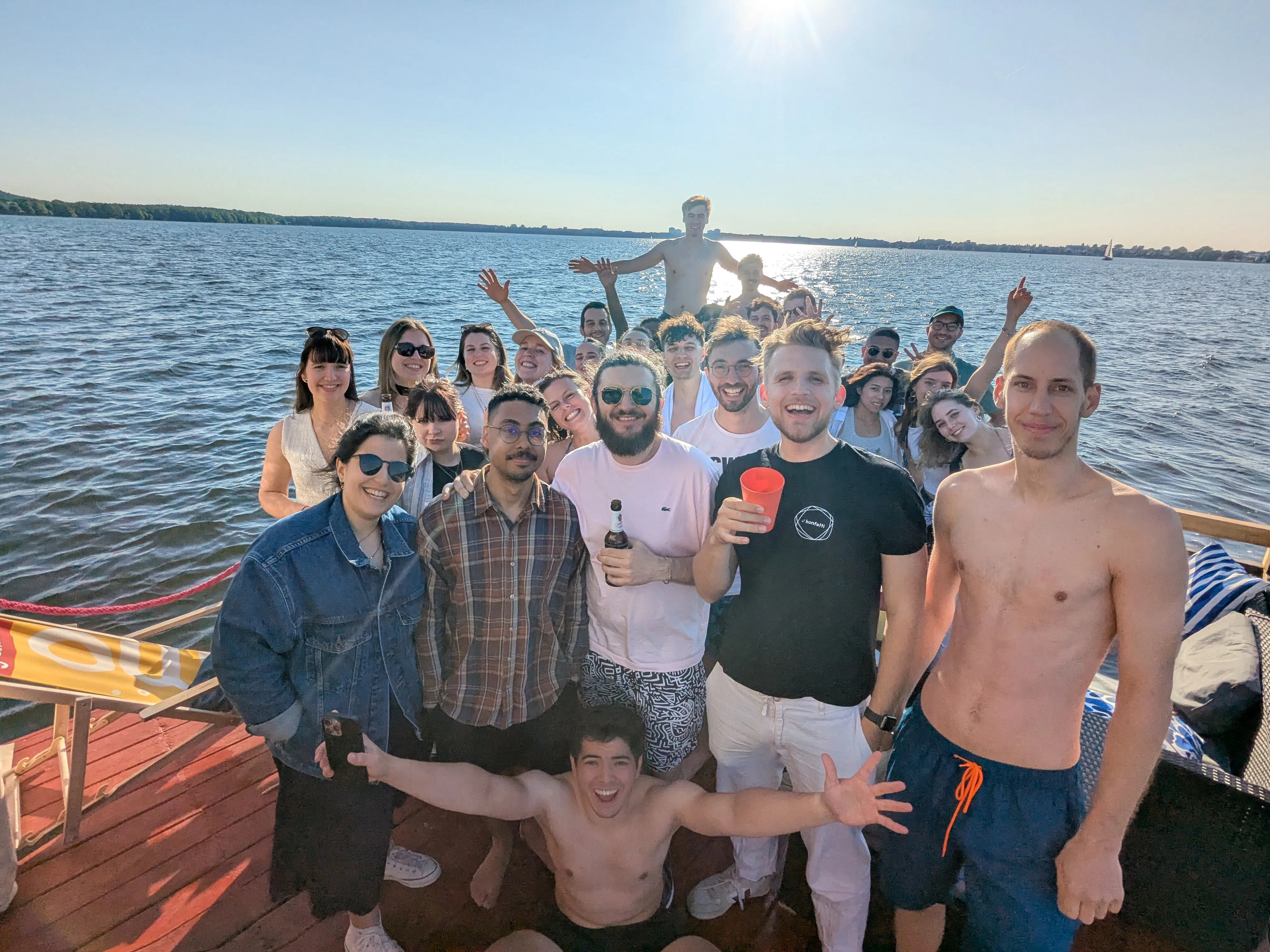 Gruppe von Freunden feiert auf Boot unter sonnigem Himmel.