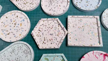 Bunte Terrazzo-Untersetzer auf grünem Raster.