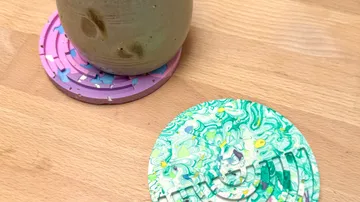 Tasse auf lila Untersetzer, bunter Untersetzer daneben.