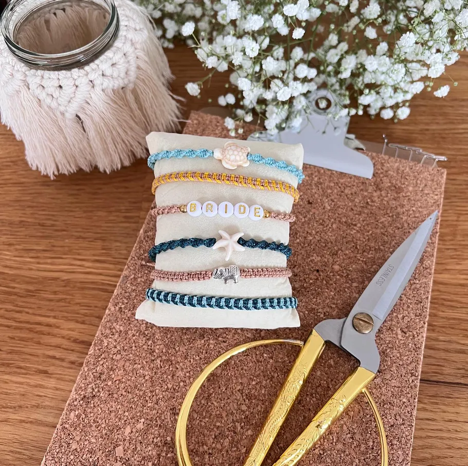 Bracelets with charms on cushion, scissors nearby.
