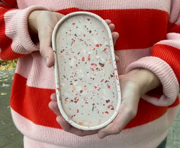 Hände halten Terrazzo-Tablett im Freien.