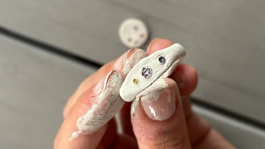 Person holding a clay object with gems.